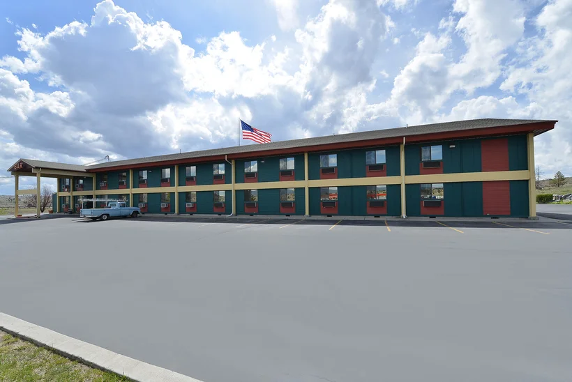 A two-story motel with a parking lot and an American flag flying above it.