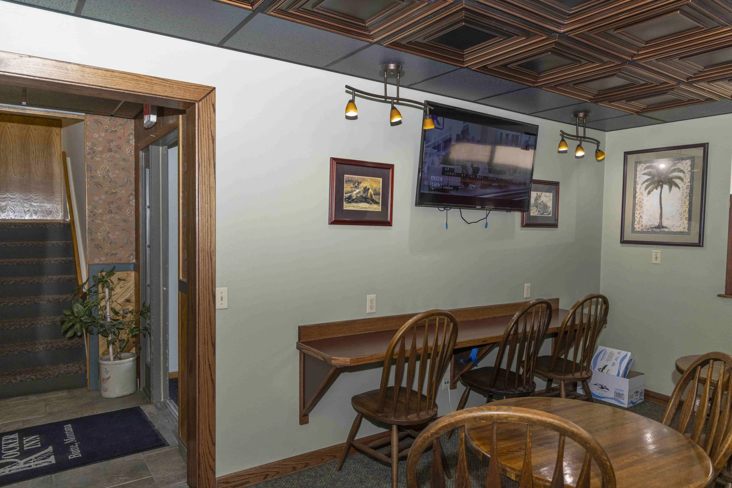 A lobby area with a desk, chairs, TV, and pictures on the wall.
