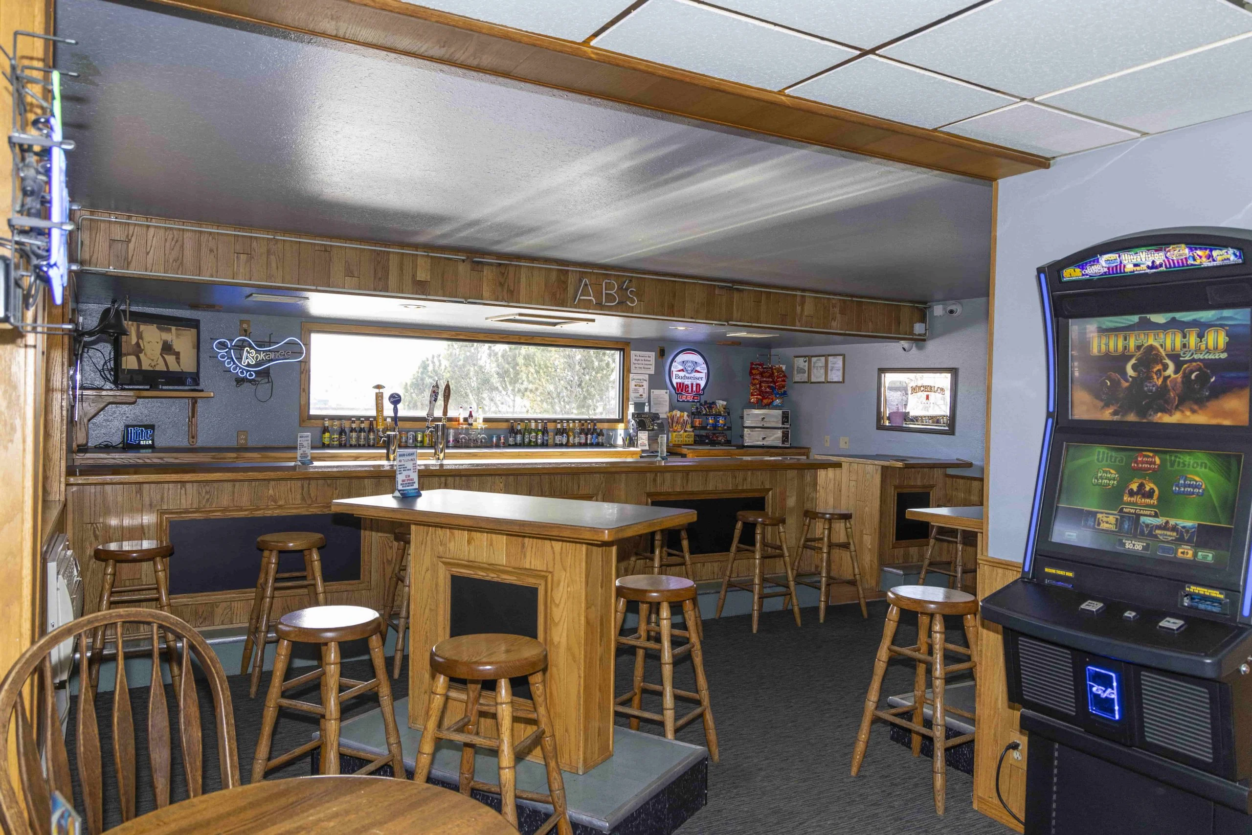 A dimly lit bar with wooden furniture and a video game machine.